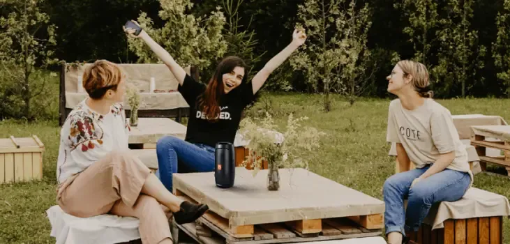 Friends listening to a WallaSound speaker at an outdoor backyard table