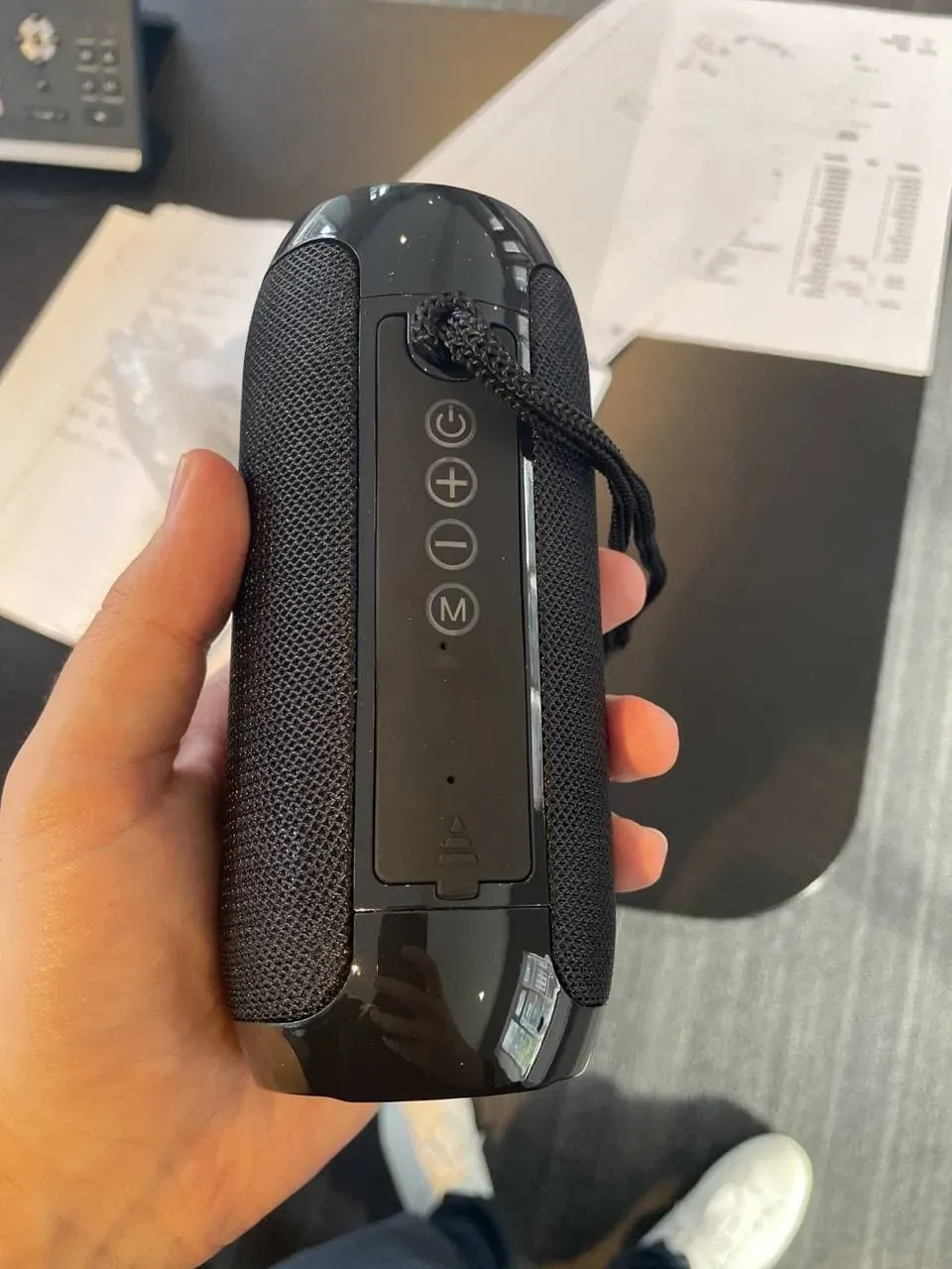 Close-up of the WallaSound speaker control buttons held in one hand
